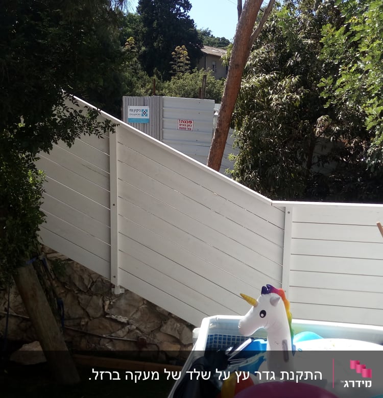 גדר עץ לבנה עם עץ וענפים